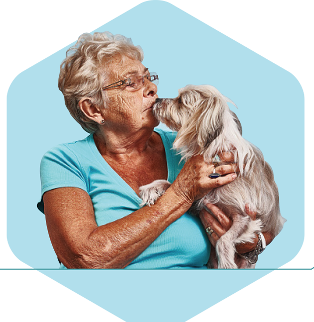 A woman holding and kissing her small dog